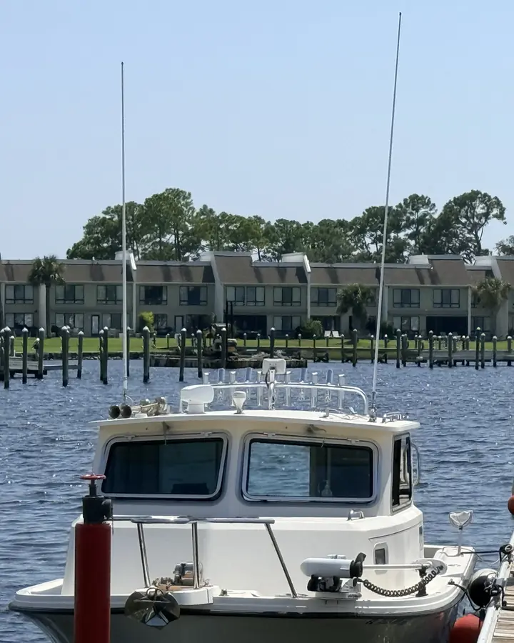 Boat docked at the Bay Point marina with waterfront townhomes across the basin, Panama City Beach.