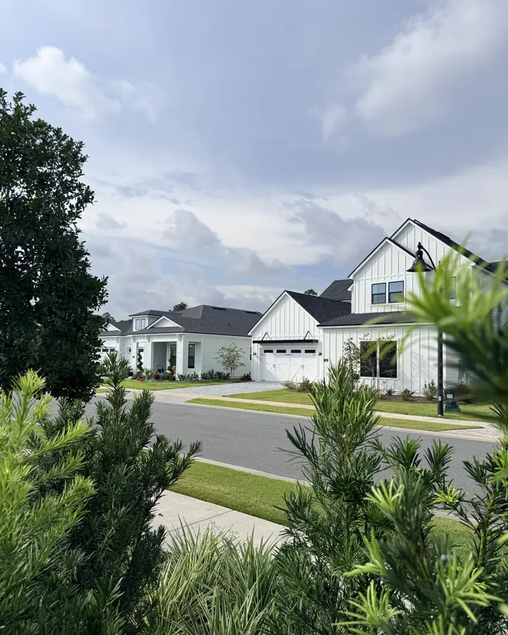 New-construction white coastal farmhouse with a two-car garage on a landscaped corner lot at Breakwater at Ward Creek.